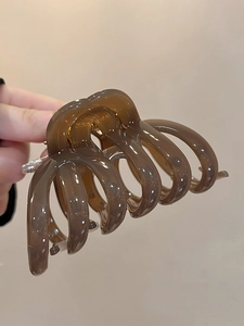 Detailed view of a transparent brown acrylic hair claw clip with a sturdy gold spring