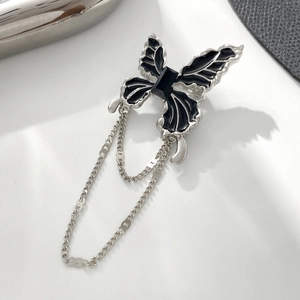 Macro detail of gothic silver butterfly brooch with black enamel and tassel chains