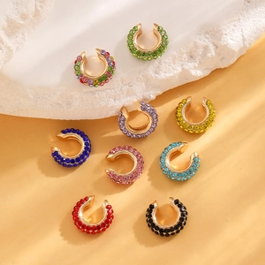 Flat lay of colorful rhinestone ear cuffs in various shades with gold metal bases