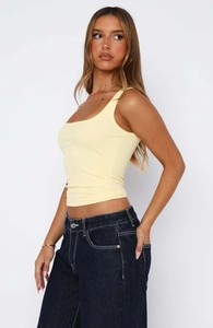 Detail view of a pale yellow ribbed knit tank top showing fabric texture and slim side fit