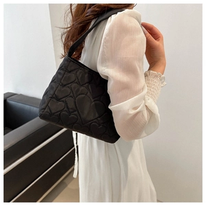 Détail du motif matelassé en cœur sur le sac fourre-tout noir avec large bandoulière