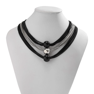 Detail of layered box chains with metallic spheres on a white fashion jewelry bust