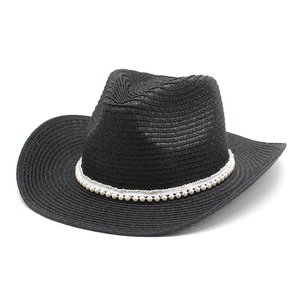 Détail d'un chapeau de cowboy en paille noire avec bande de perles et large bord