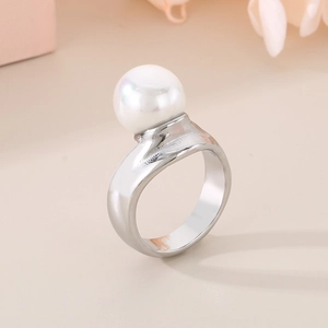Vista dettagliata di un anello in titanio argento con una grande perla bianca su fondo beige