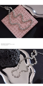 Macro view of silver cross chain necklace showing intricate floral links and extender