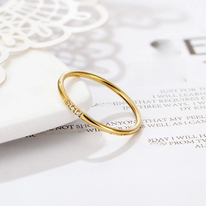 Close-up of minimalist gold ring with three zircon stones on a white background