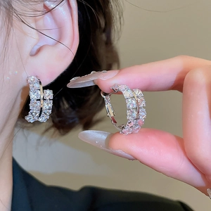 Détail de boucles d'oreilles créoles argentées avec double rangée de zircons et cristaux carrés