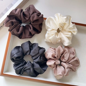 Detail of satin scrunchie set in brown, white, and black on a white display tray
