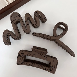 Close-up of matte brown hair claws with black marble patterns in various shapes