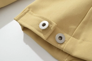 Detailed macro view of khaki twill fabric texture and silver metal snap buttons on jacket