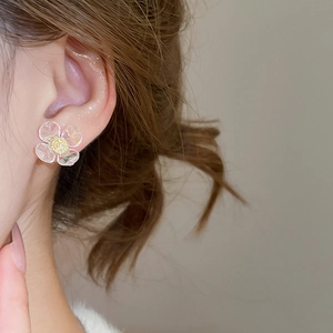 Detail of floral earring with translucent petals and gold center worn by a model