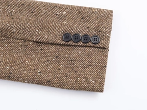 Gros plan sur la texture tweed chevrons marron et les quatre boutons de la manche