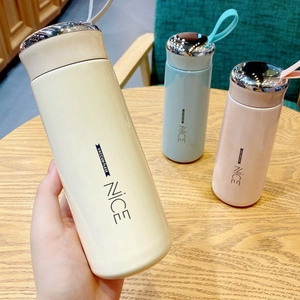 Three colorful vacuum flasks with metal lids and silicone handles on a wooden table