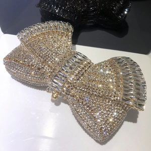 Macro detail of sparkling bow-shaped rhinestone clutch bag on a reflective surface
