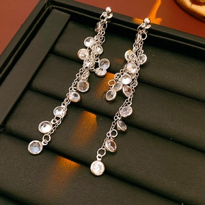 Macro shot of sparkling round cubic zirconia tassel earrings on a black jewelry tray