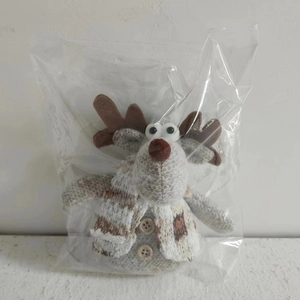 Close-up of plush reindeer Christmas ornament with grey knit texture and plaid scarf