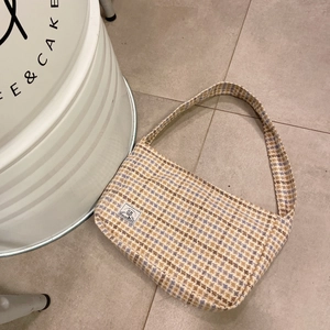 Detail of checkered woolen texture on a navy blue and beige rectangular shoulder bag