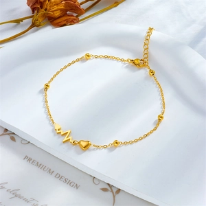 Minimalist gold titanium steel heartbeat heart chain anklet on a white display plate