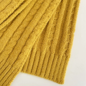 Macro shot of ginger yellow knitted scarf with thick cable knit texture for winter