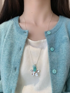 Detailansicht der floralen Katzenaugen-Halskette an Model mit hellblauem Strickoberteil