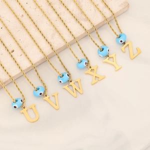 Gold twist chain necklaces with blue evil eye and alphabet pendants on marble