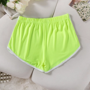 Flat lay of neon yellow elastic sports shorts with white piping and decorative items