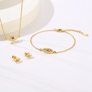 Vue détaillée de l'ensemble de bijoux oeil maléfique doré avec collier, bracelet et boucles