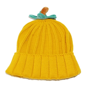 Detailed view of yellow knitted pumpkin hat featuring green stem and leaf decorations