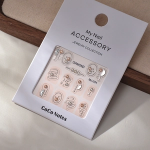 Detail view of silver and gold geometric nail charms with crystals on a white card display