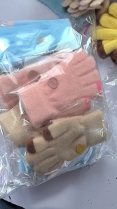 Close-up of knitted winter gloves for children featuring cute smiley face buttons in various colors