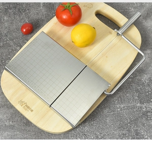 Detail of cheese slicer with stainless steel scale grid on a wooden board base