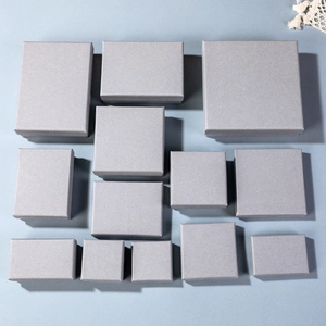 Detailed flat lay of gray jewelry gift boxes in various sizes on light blue background