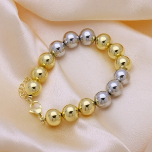 Detailed shot of two-tone gold and silver beaded bracelet on champagne silk background