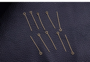 Detailed view of ten golden stainless steel eye pins on black textured leather surface
