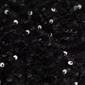 Macro shot of black sequin fabric detail showing high-shine metallic texture and stitching