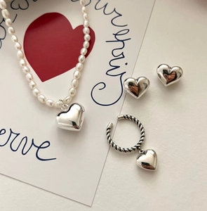 Detailed set of silver heart jewelry featuring pearl necklace, earrings and textured ring