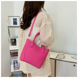 Détail du sac seau en cuir grainé rose avec poignées et pieds de protection en métal