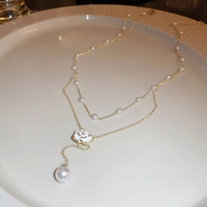 Close-up of double-layer gold camellia necklace with white rose pendant and pearls