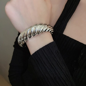 Detail of chunky silver twisted open cuff bracelet on wrist for a modern aesthetic
