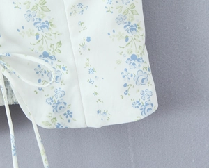 Detail of white floral top with blue prints and delicate lace-up ribbon strings