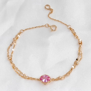 Detailed close-up of S925 silver 14k gold plated bracelet with pink gemstone on white silk