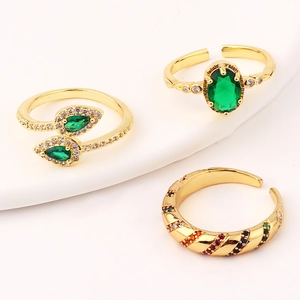 Close-up of three gold rings with emerald green and multicolor zircon stones