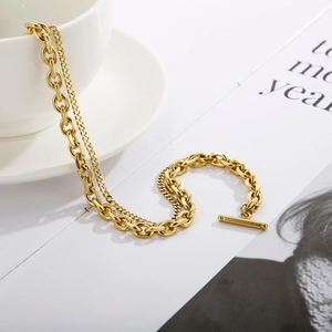 Close-up of gold double-layer titanium necklace with OT toggle clasp on a white cup