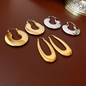 Macro shot of U-shaped gold and silver earrings on a dark textured leather background