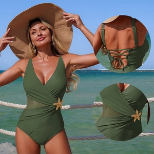 Olive green one-piece swimsuit with mesh panels and starfish buckle on beach background