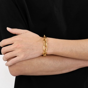 Macro shot of a thick golden link chain bracelet on a wrist with premium metallic texture