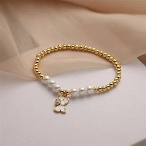 Detail of gold beaded bracelet with pearls and a sparkling white elephant charm