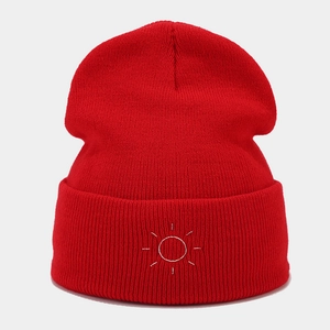 Detailed view of red knitted beanie featuring high-quality white sun embroidery texture