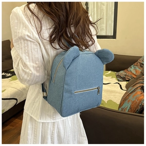 Close-up of blue denim backpack with cute ear design shown on model's back