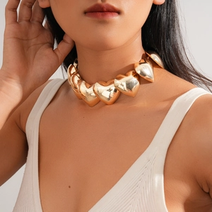 Detail shot of a chunky gold heart choker necklace on model focusing on texture